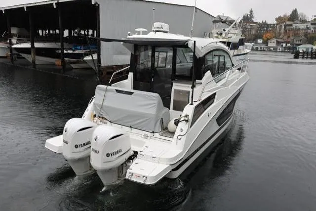 Slide: The Image of 2021 Four Winns V355 Coupe boat with twin Yamaha engines on a calm waterway. - 45