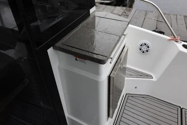 Slide: The Image of 2021 Four Winns V355 Coupe boat deck with sleek countertop and storage. - 7