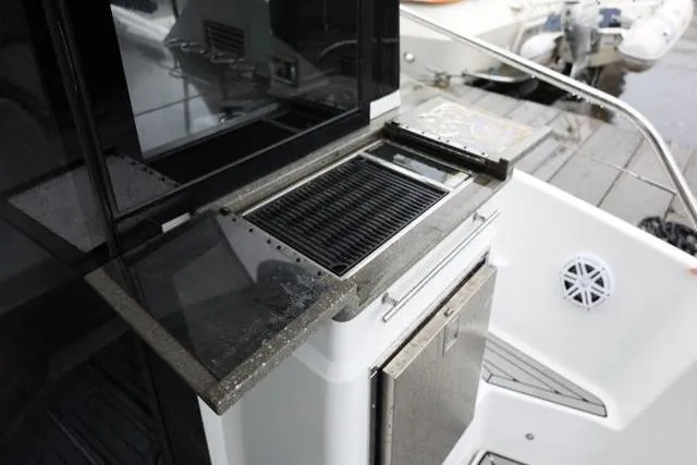 Slide: The Image of Outdoor kitchen area on 2021 Four Winns V355 Coupe boat, featuring a grill and storage. - 8