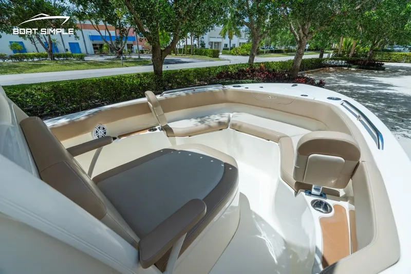 Slide: The Image of 2023 Scout 215 XSF boat interior with cushioned seating and cup holders, parked outdoors. - 13