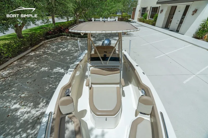 Slide: The Image of 2023 Scout 215 XSF boat with beige seating, parked outdoors near a building. - 14
