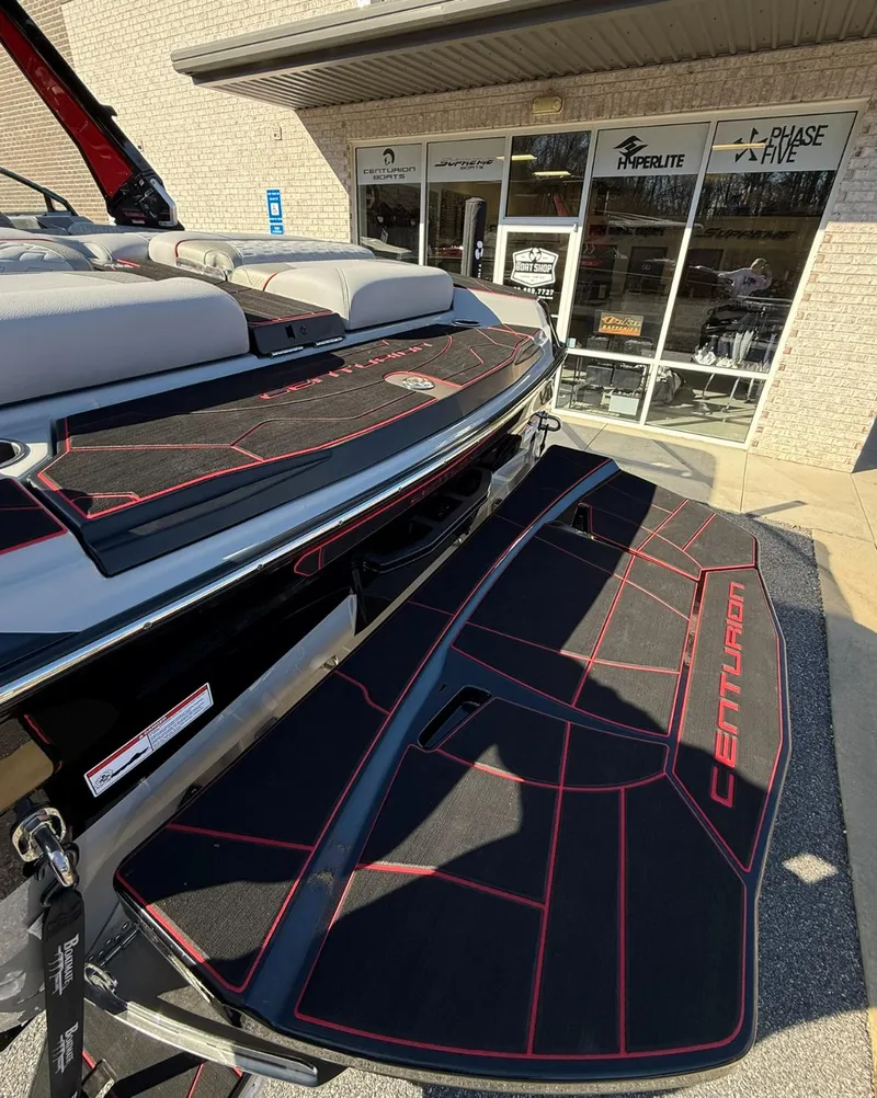 Slide: The Image of 2025 Centurion Ri245 boat with sleek black and red detailing, displayed outside a showroom. - 17