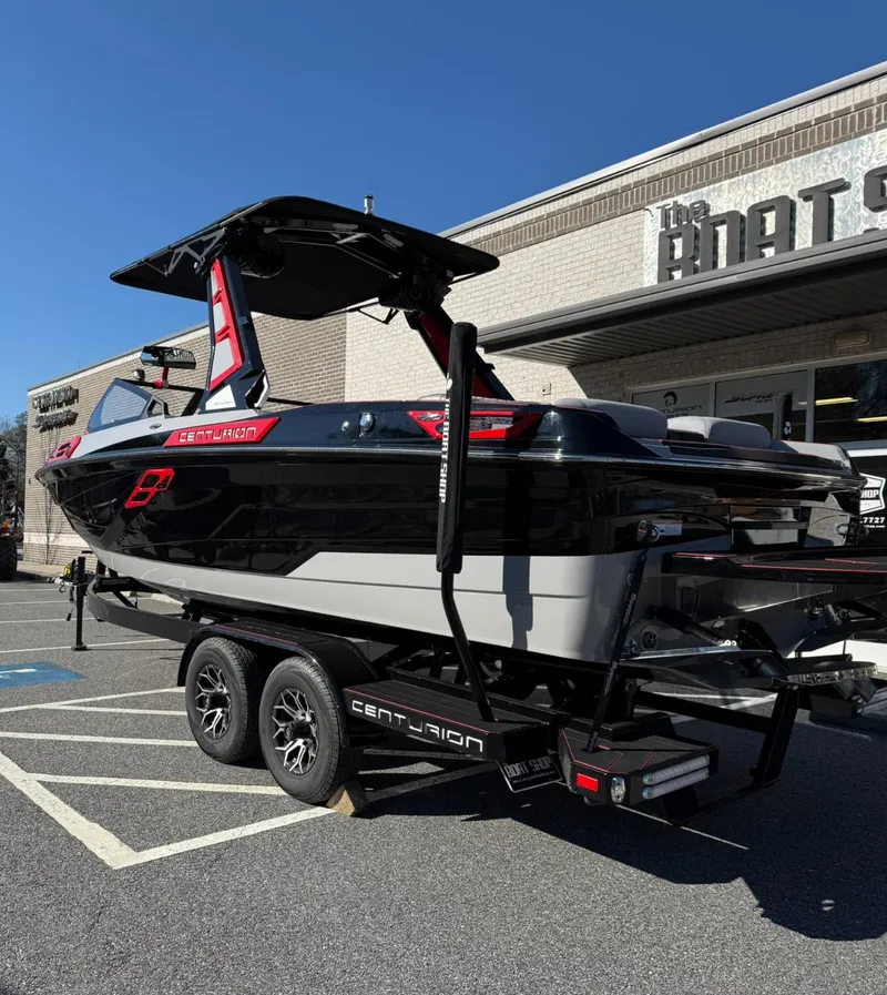 Slide: The Image of 2025 Centurion Ri245 boat on trailer outside dealership, under clear blue sky. - 4