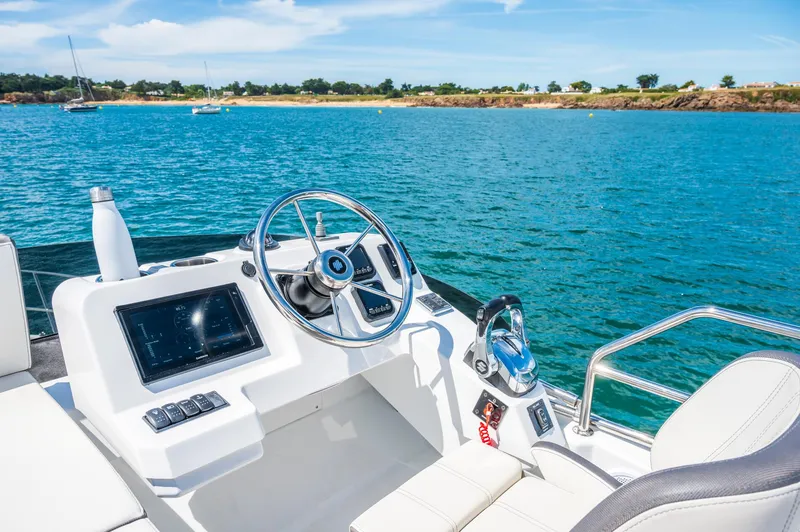 Slide: The Image of 2025 Beneteau Antares 11 Fly helm with ocean view, featuring modern controls and steering wheel. - 14