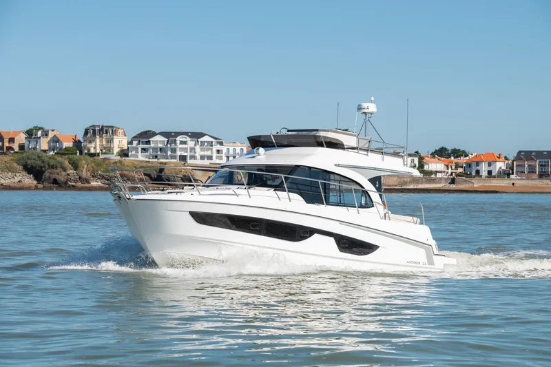 Slide: The Image of 2025 Beneteau Antares 11 Fly cruising on calm waters near coastal homes. - 19