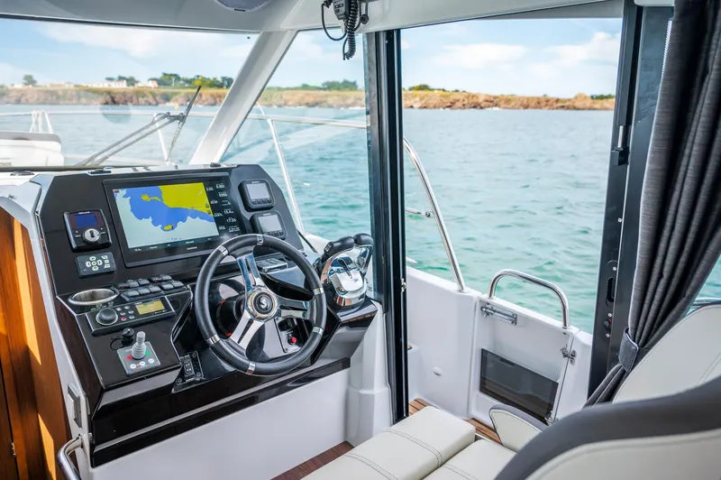 Slide: The Image of 2025 Beneteau Antares 11 Fly cockpit with modern navigation system, steering wheel, and sea view. - 36