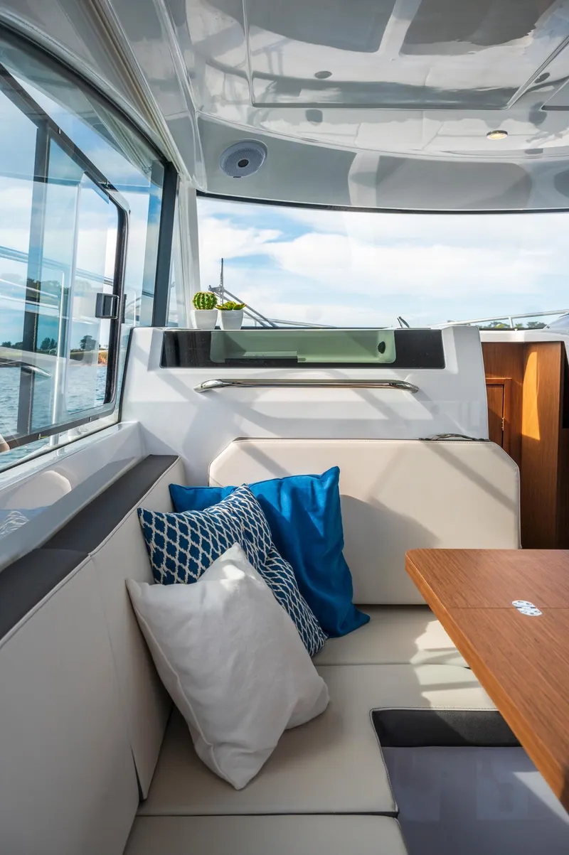Slide: The Image of 2025 Beneteau Antares 11 Fly interior with cushions and wooden table, showcasing modern design. - 44
