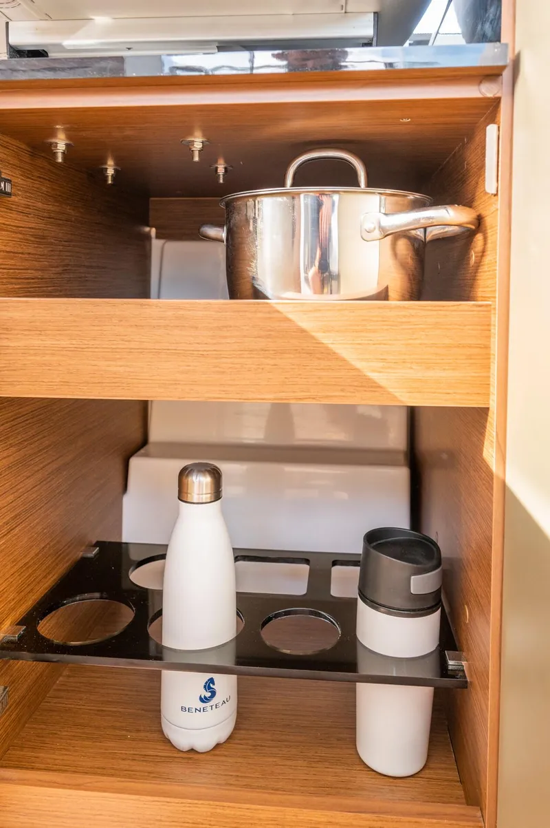 Slide: The Image of 2025 Beneteau Antares 11 Fly kitchen storage with cookware and bottles. - 47