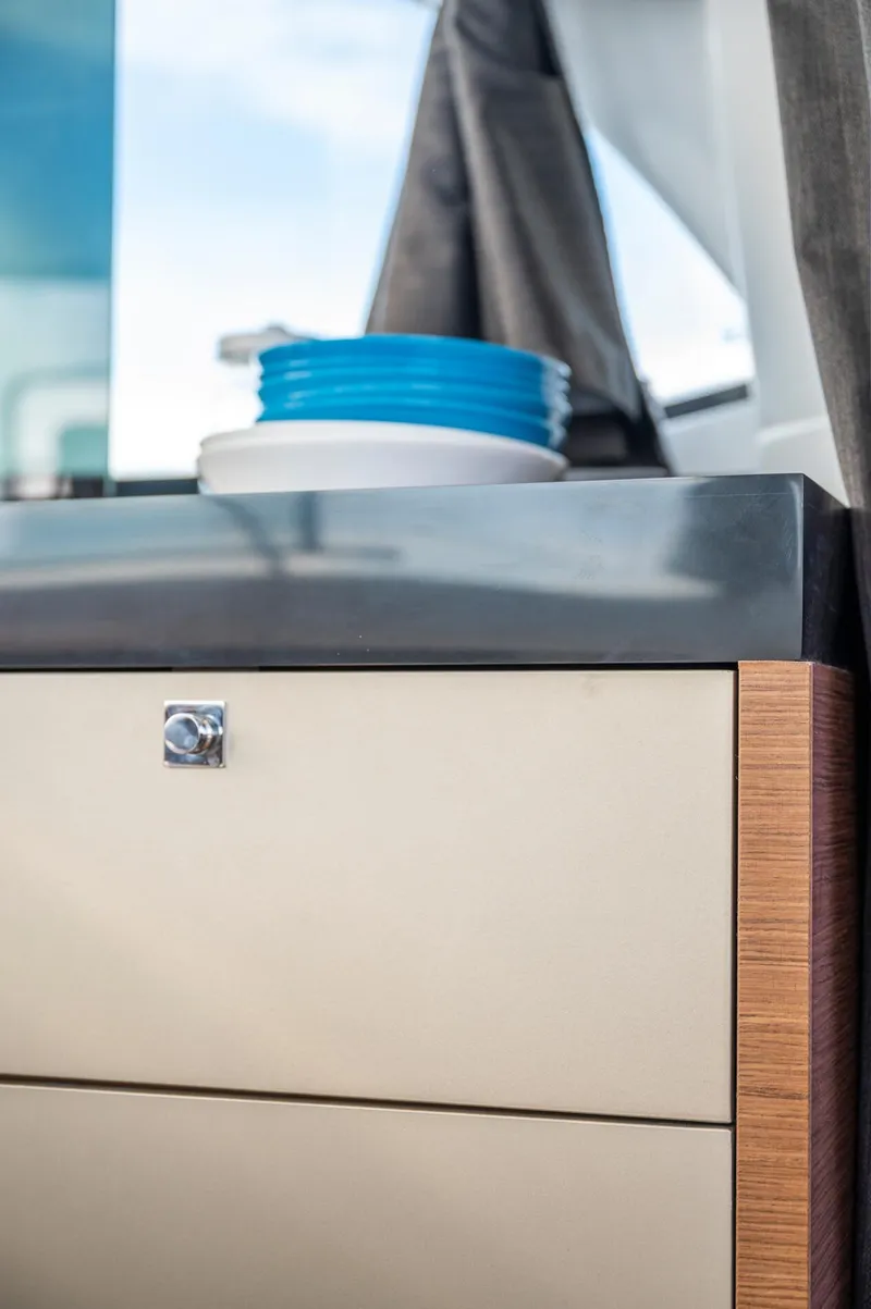 Slide: The Image of 2025 Beneteau Antares 11 Fly interior detail with modern cabinetry and blue dishware. - 49