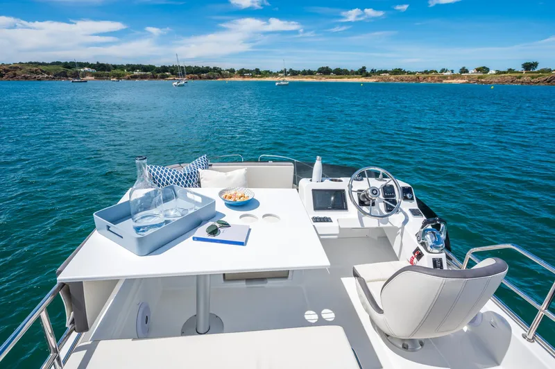 Slide: The Image of 2025 Beneteau Antares 11 Fly yacht deck with table, chairs, and ocean view. - 5