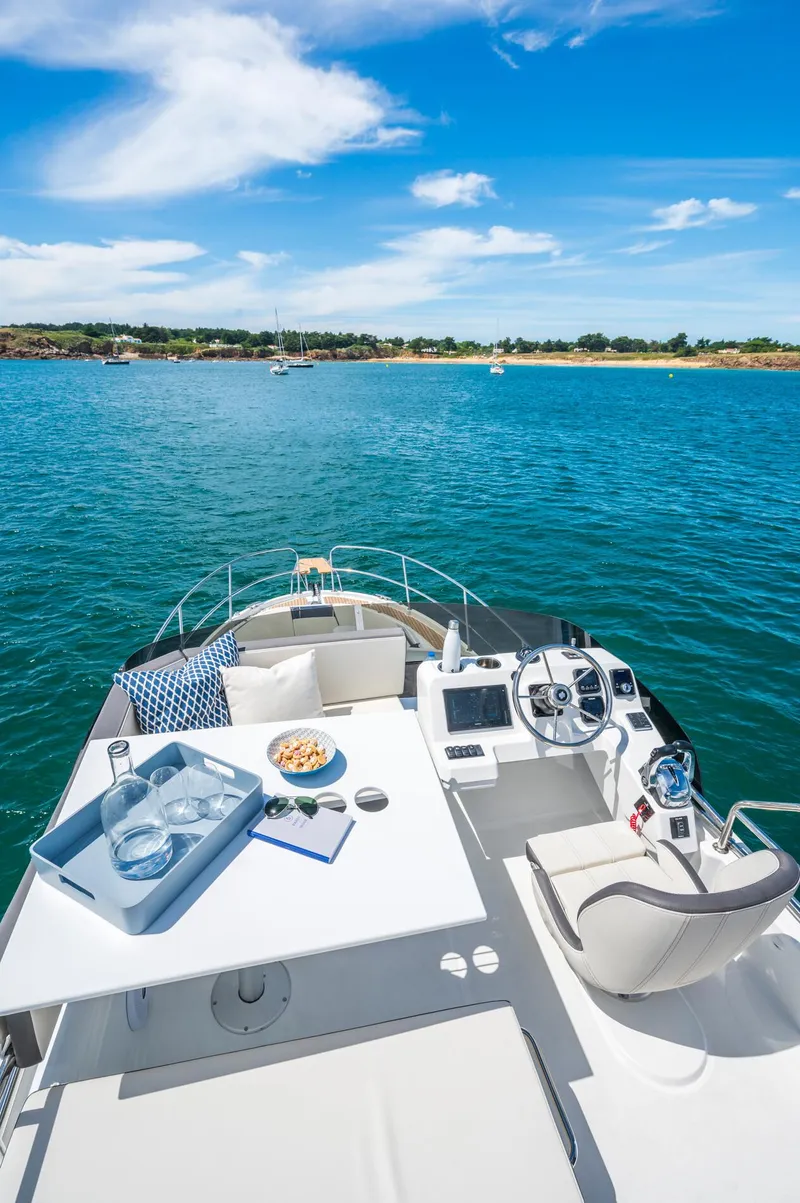 Slide: The Image of 2025 Beneteau Antares 11 Fly yacht on serene blue water, featuring a modern helm and seating area. - 6