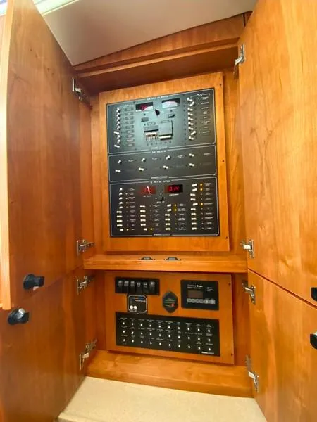 Slide: The Image of Electrical panel inside 2022 Albemarle 360 Express Fisherman boat, featuring wooden cabinetry. - 59