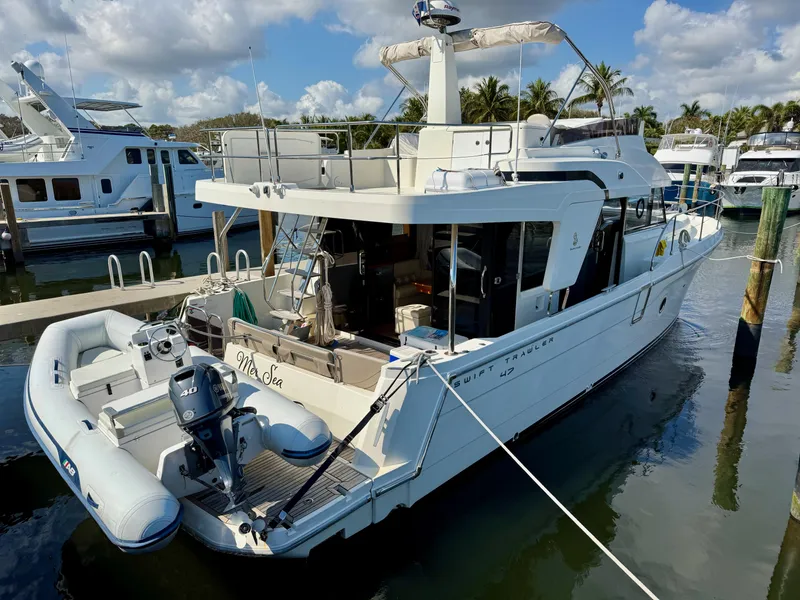 Slide: The Image of 2020 Beneteau Swift Trawler 47 docked, featuring spacious deck and inflatable dinghy. - 0