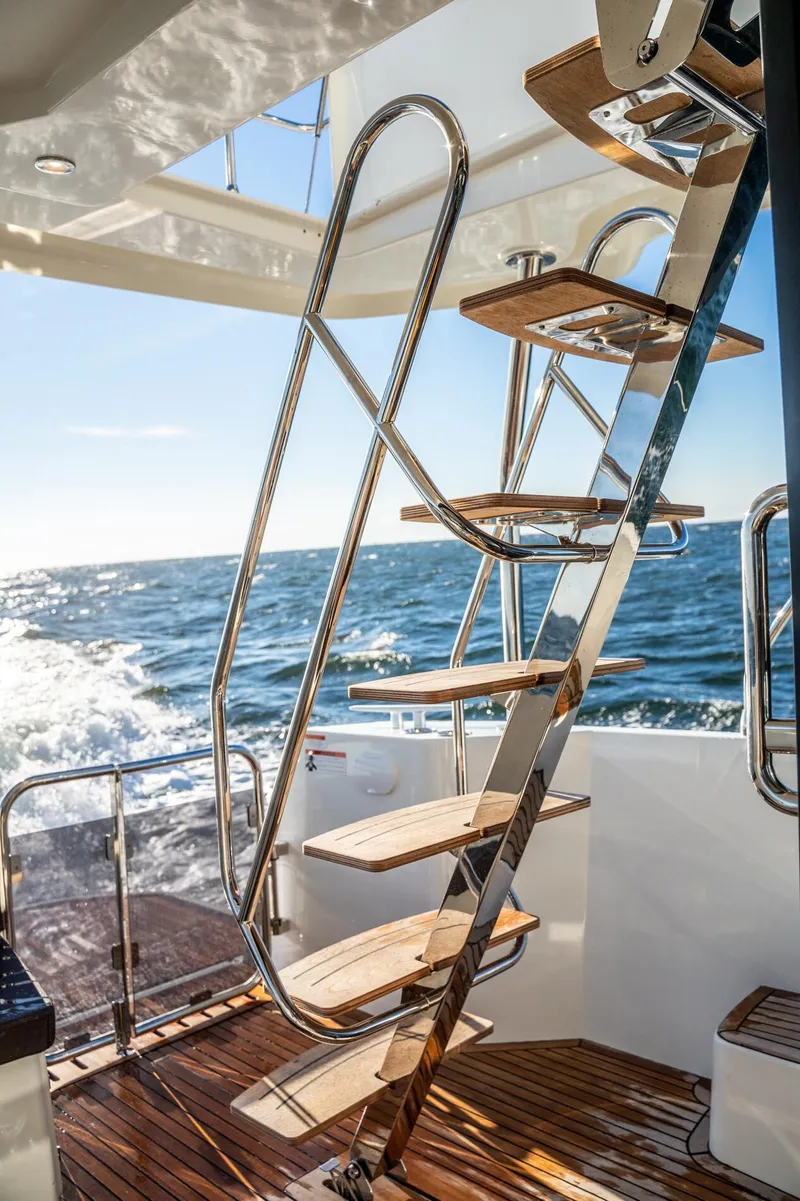 Slide: The Image of 2020 Beneteau Swift Trawler 47, elegant staircase, ocean backdrop, sunny day. - 13