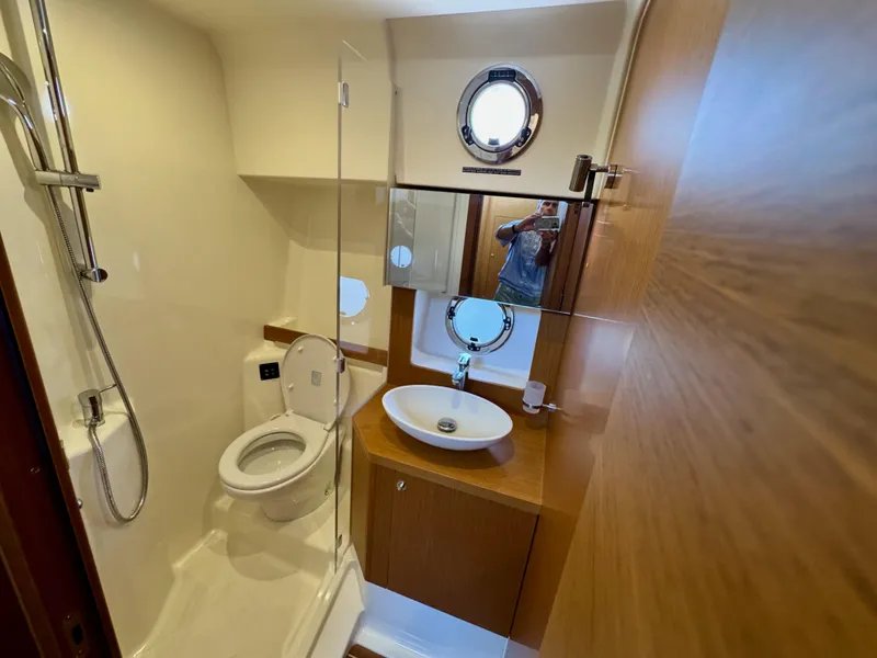 Slide: The Image of 2020 Beneteau Swift Trawler 47 bathroom with shower, sink, and porthole window. - 15