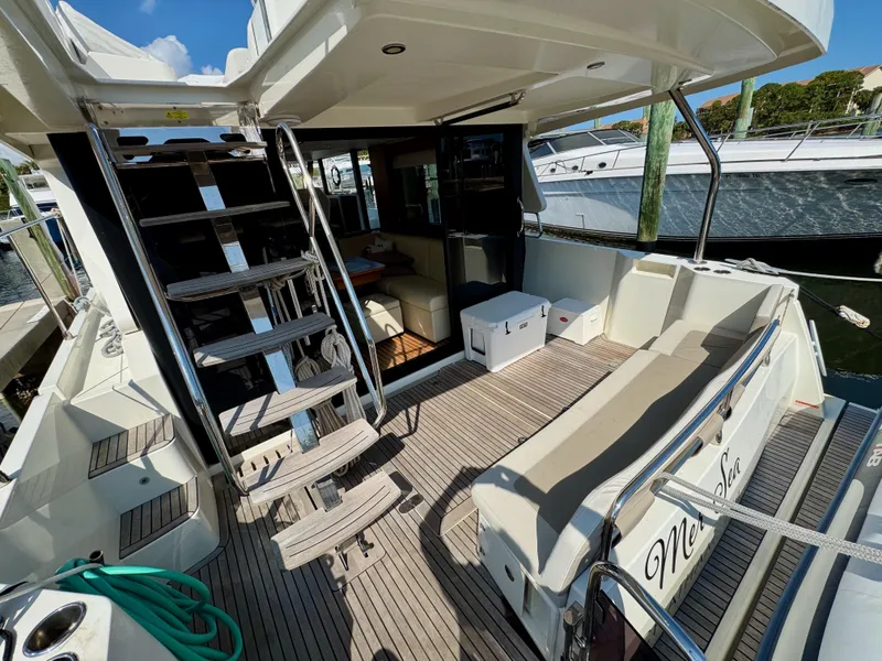 Slide: The Image of 2020 Beneteau Swift Trawler 47, spacious deck with seating and ladder, docked at marina. - 20