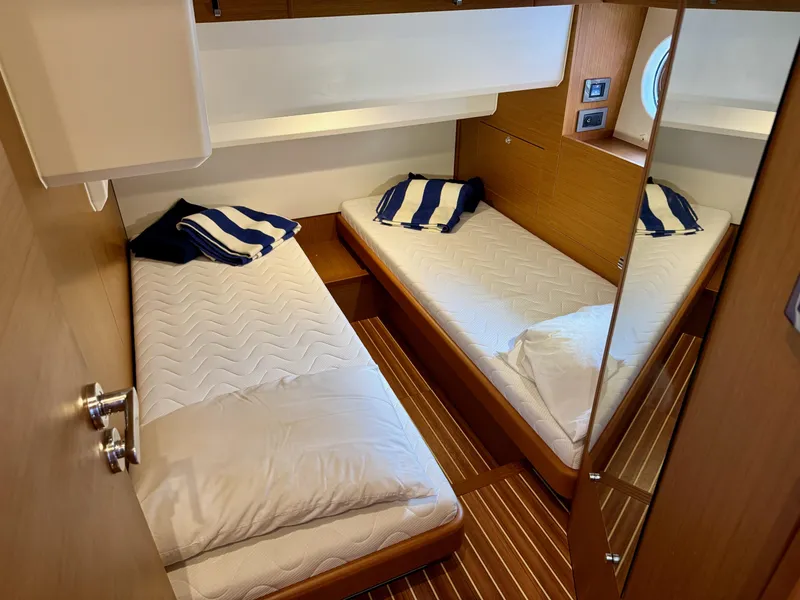 Slide: The Image of 2020 Beneteau Swift Trawler 47 cabin with twin beds and striped pillows. - 21