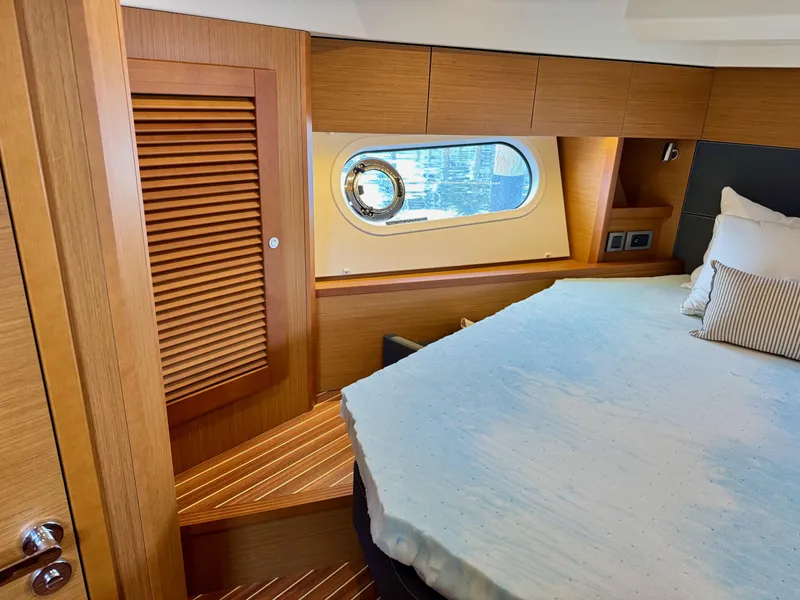Slide: The Image of 2020 Beneteau Swift Trawler 47 cabin with wooden interior and porthole window. - 22