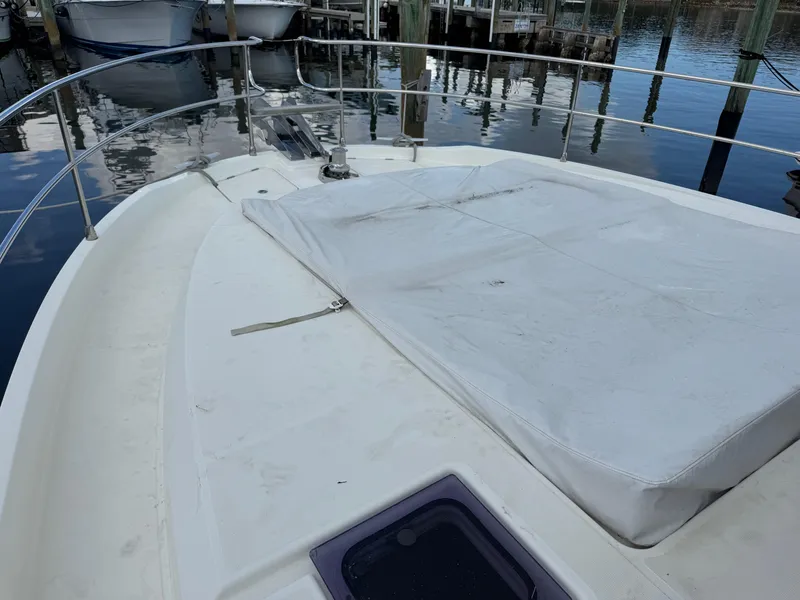 Slide: The Image of 2020 Beneteau Swift Trawler 47 bow view at marina, featuring covered deck area. - 24