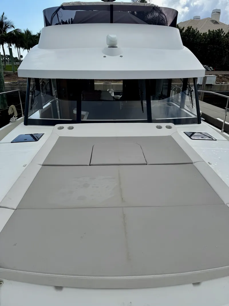Slide: The Image of 2020 Beneteau Swift Trawler 47, front view, docked, showcasing spacious deck and sleek design. - 25