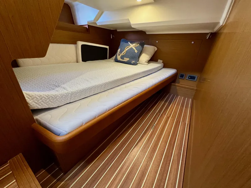 Slide: The Image of 2020 Beneteau Swift Trawler 47 cabin with wooden interior and cozy bedding. - 6