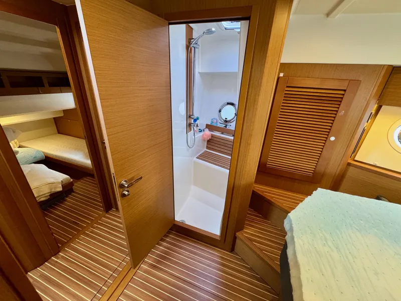 Slide: The Image of 2020 Beneteau Swift Trawler 47 interior with wood finish, bathroom, and cozy sleeping area. - 8