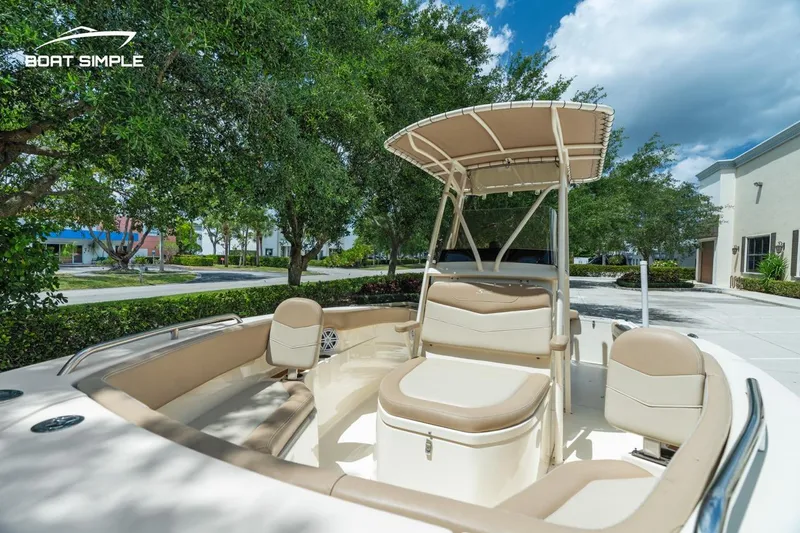 Slide: The Image of 2023 Scout 215 XSF boat with seating and canopy, parked outdoors under trees. - 11