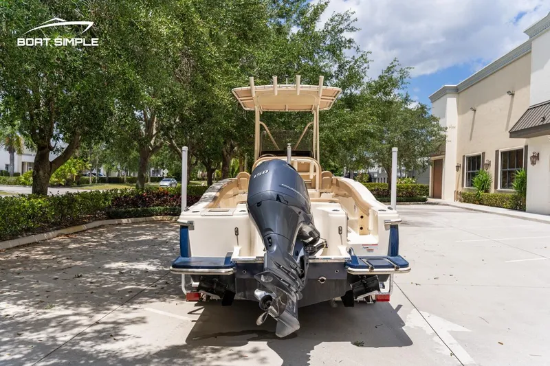 Slide: The Image of 2023 Scout 215 XSF boat with outboard motor, parked outdoors on a sunny day. - 6