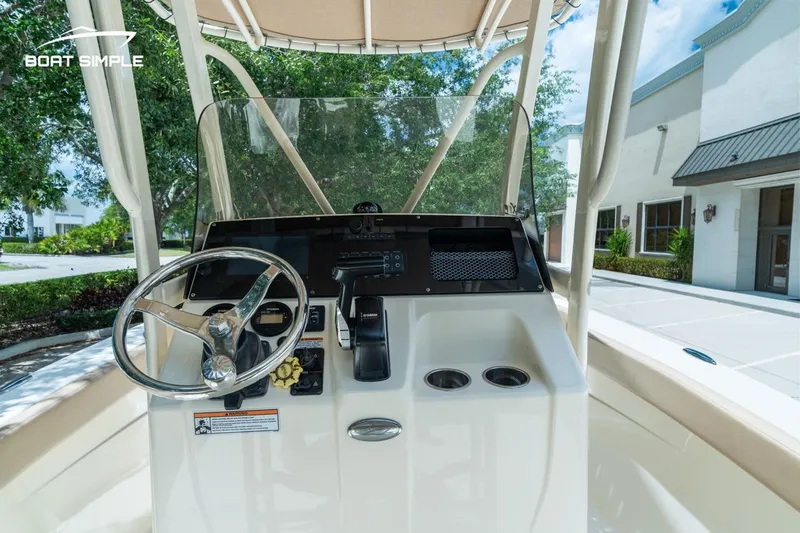 Slide: The Image of 2023 Scout 215 XSF boat console with steering wheel and controls, parked outdoors. - 8