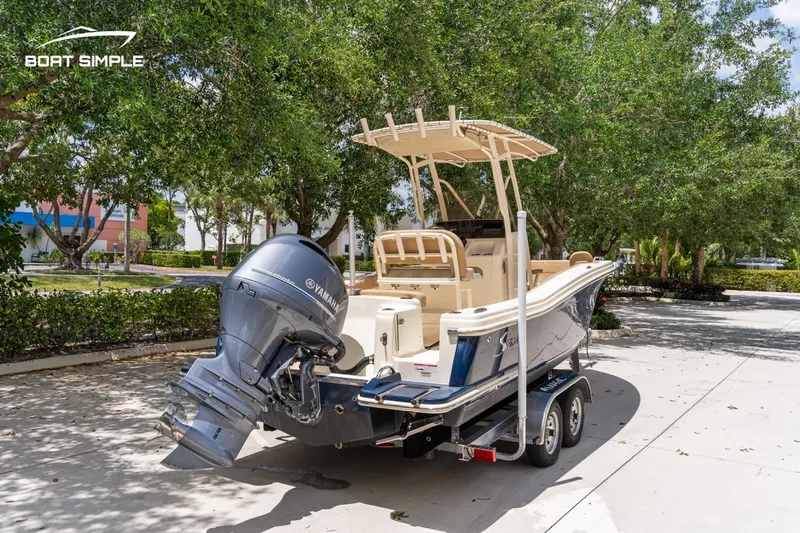 Slide: The Image of 2023 Scout 215 XSF boat on trailer, parked outdoors with trees in the background. - 3