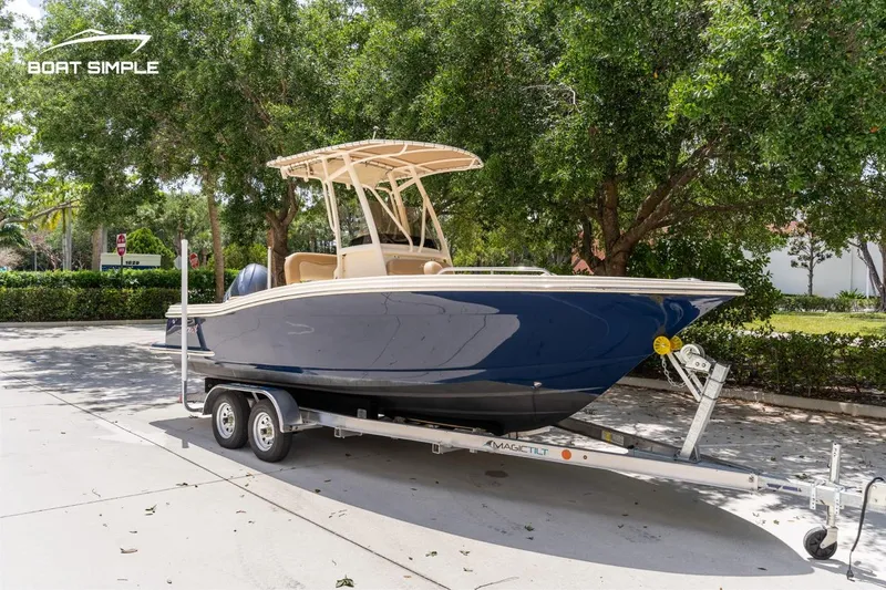 Slide: The Image of 2023 Scout 215 XSF boat on trailer, parked outdoors with trees in background. - 4