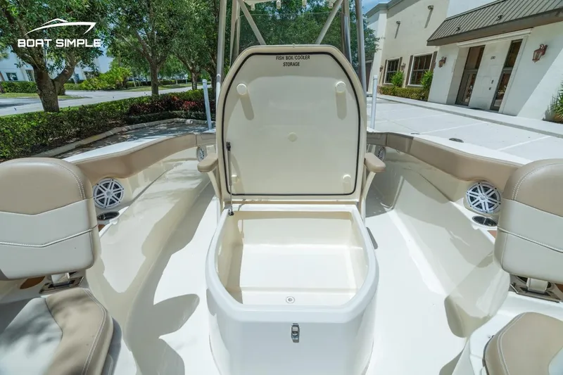Slide: The Image of 2023 Scout 215 XSF boat interior with open storage compartment, beige seating, and outdoor setting. - 9