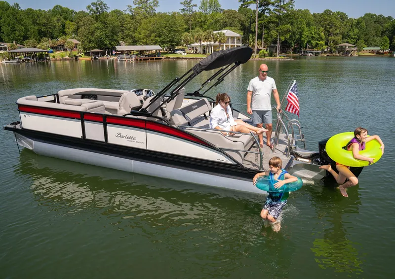Slide: The Image of 2025 Barletta Aria 24UC pontoon boat on a lake with people enjoying water activities. - 11