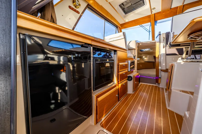 Slide: The Image of Interior of 2016 Cutwater 30 Command Bridge with modern kitchen and wood flooring. - 16