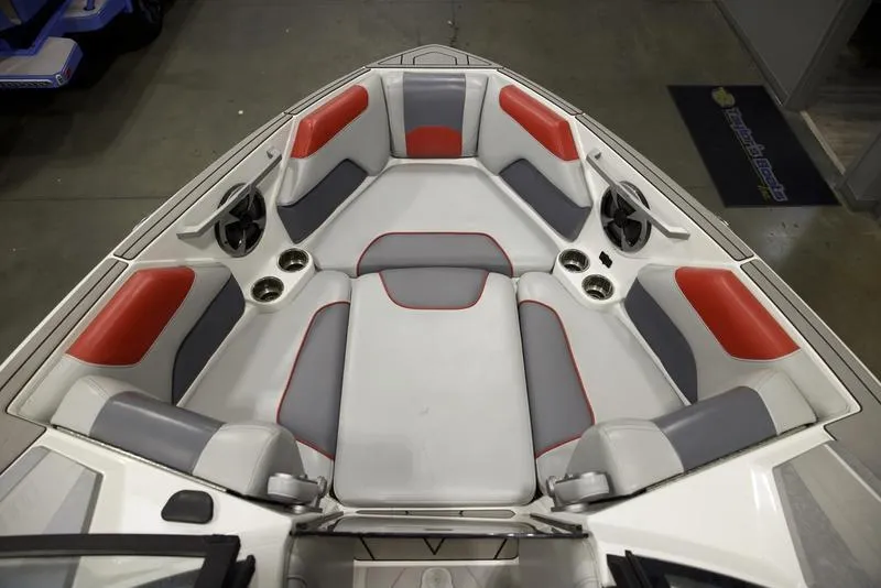 Slide: The Image of 2021 Malibu 25 LSV boat interior with red and gray seating, cup holders, and speakers. - 13