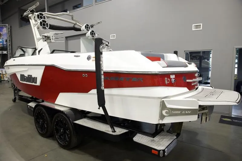 Slide: The Image of 2021 Malibu 25 LSV boat in showroom, red and white design, on trailer. - 4