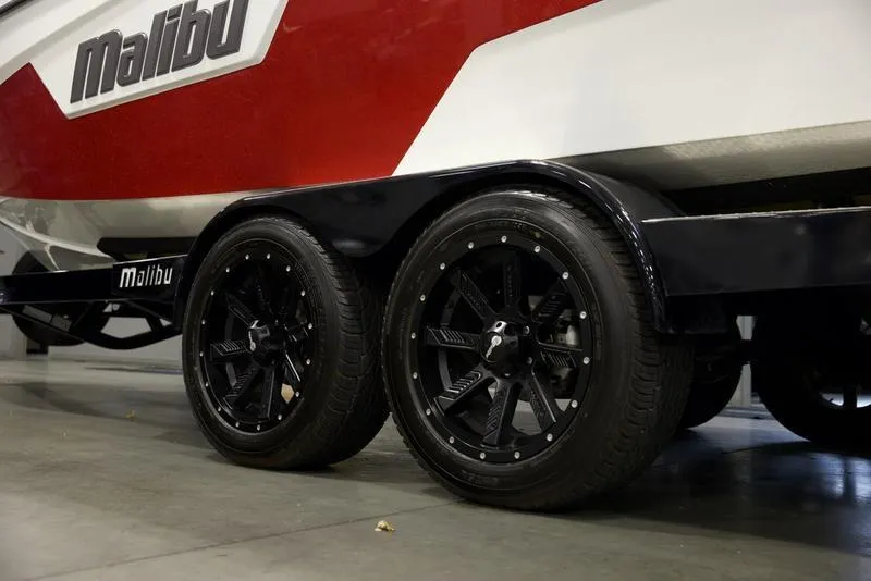 Slide: The Image of 2021 Malibu 25 LSV boat trailer with black wheels, red and white design. - 6