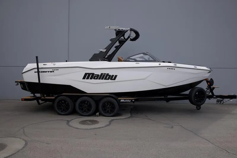 Slide: The Image of 2025 Malibu 25 LSV boat on trailer, sleek design, white exterior, parked outdoors. - 1