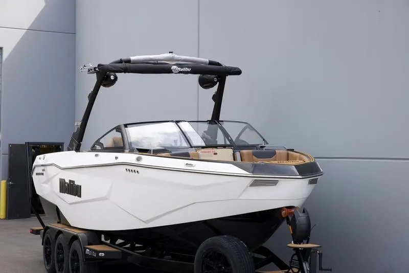 Slide: The Image of 2025 Malibu 25 LSV boat on trailer, sleek design, parked near a gray wall. - 9