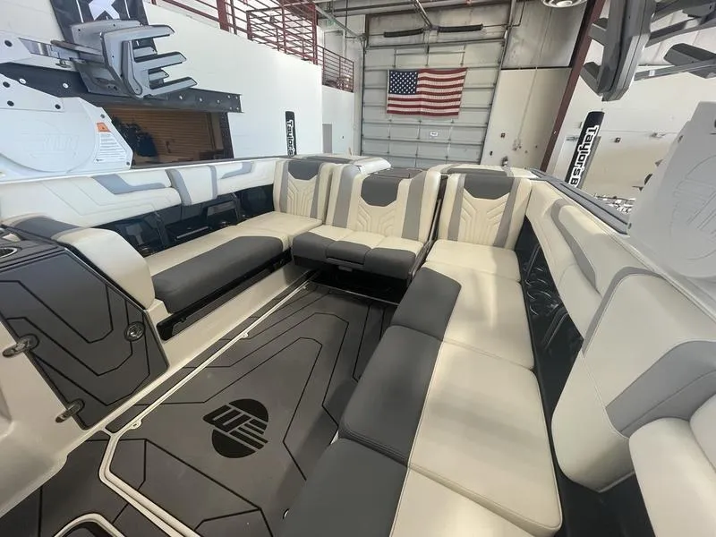 Slide: The Image of 2025 Malibu 25 LSV boat interior with luxurious seating in a showroom. - 13