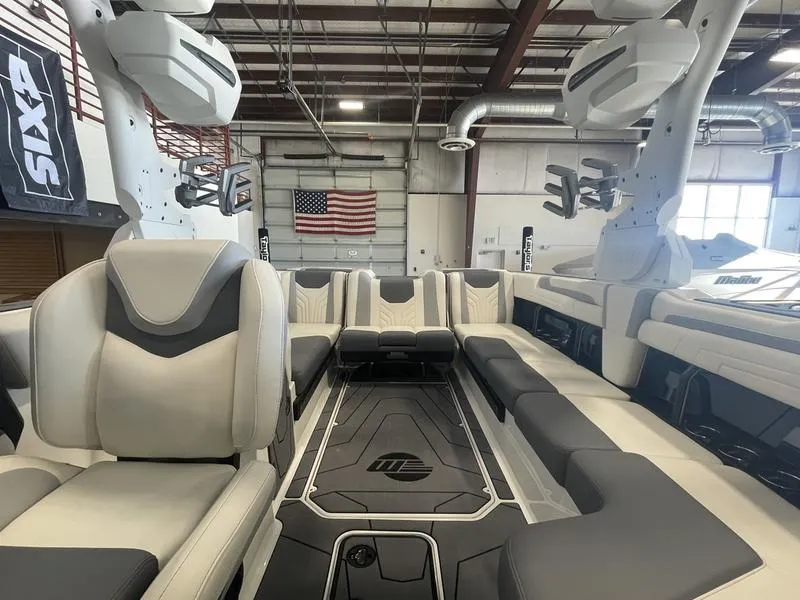 Slide: The Image of 2025 Malibu 25 LSV boat interior with luxurious seating in a warehouse setting. - 17