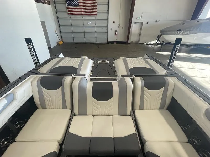 Slide: The Image of 2025 Malibu 25 LSV boat interior with stylish seating in a garage setting. - 18
