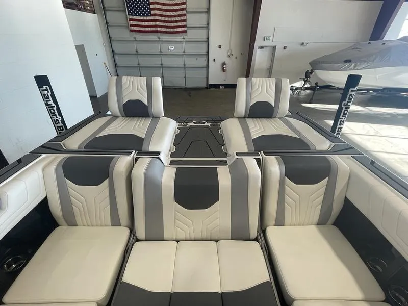 Slide: The Image of 2025 Malibu 25 LSV boat interior with gray and white seating in a garage. - 20