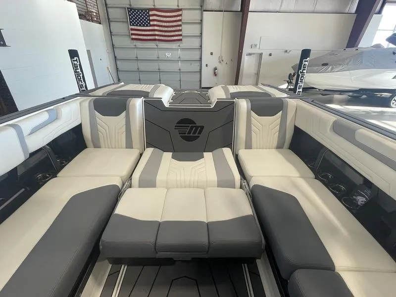 Slide: The Image of 2025 Malibu 25 LSV boat interior with gray and white seating in a showroom. - 23