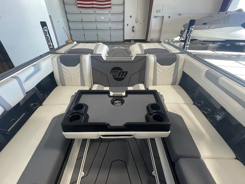 Slide: The Image of 2025 Malibu 25 LSV boat interior with seating and table, in a garage setting. - 24
