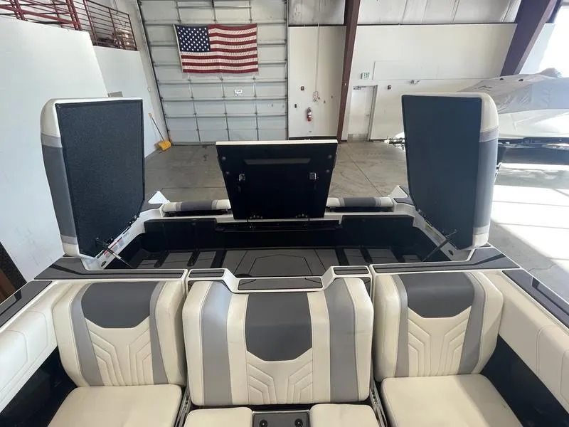 Slide: The Image of 2025 Malibu 25 LSV boat interior with open storage compartments in a garage setting. - 26