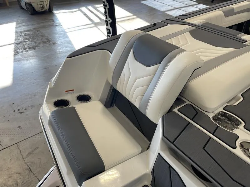 Slide: The Image of 2025 Malibu 25 LSV boat interior with gray and white seating and cup holders. - 28