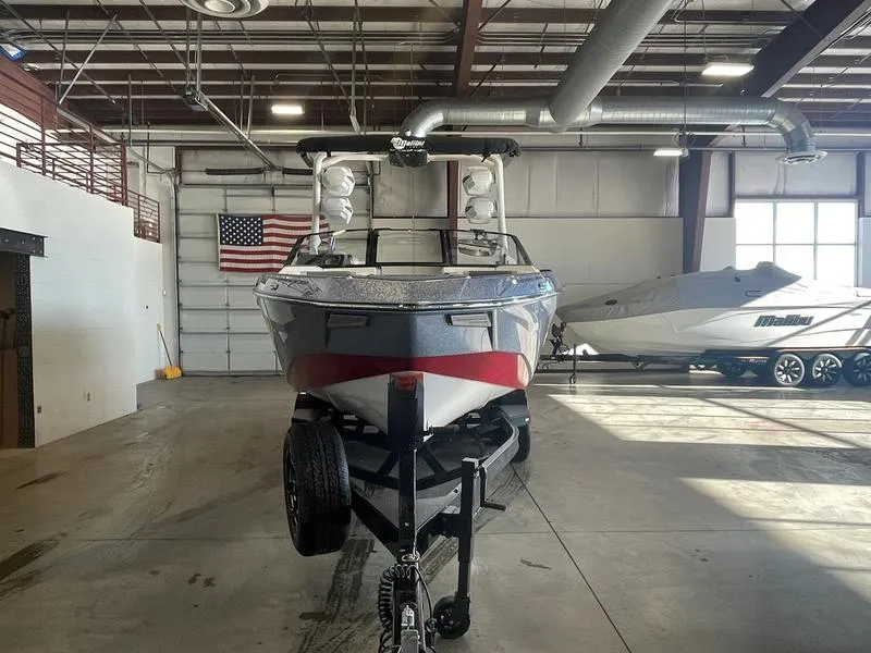 Slide: The Image of 2025 Malibu 25 LSV boat in a warehouse, front view, with American flag in background. - 4
