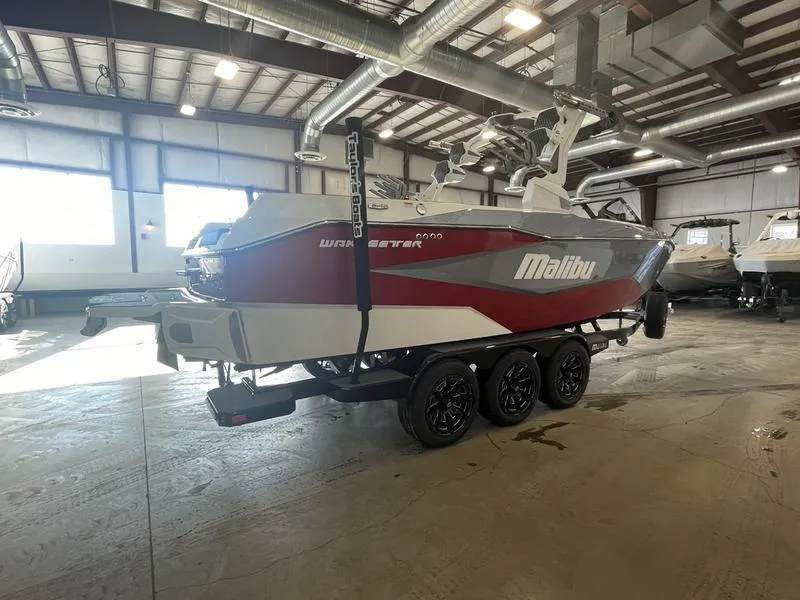 Slide: The Image of 2025 Malibu 25 LSV boat in a warehouse, featuring a sleek red and white design. - 7