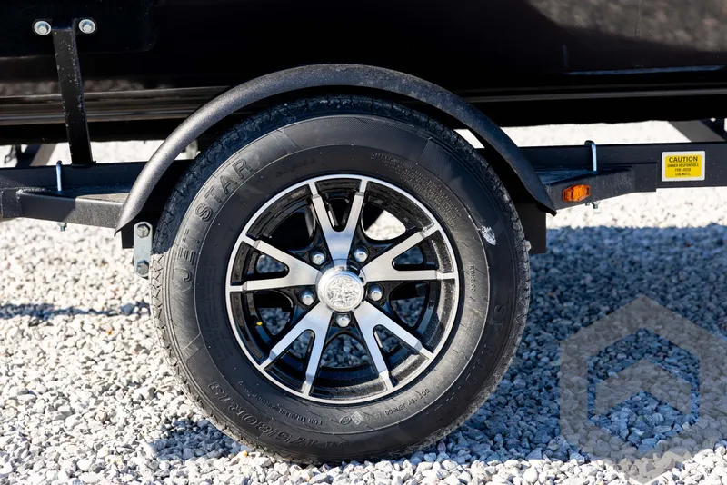 Slide: The Image of 2025 G3 Sportsman 1610 trailer wheel on gravel surface. - 13